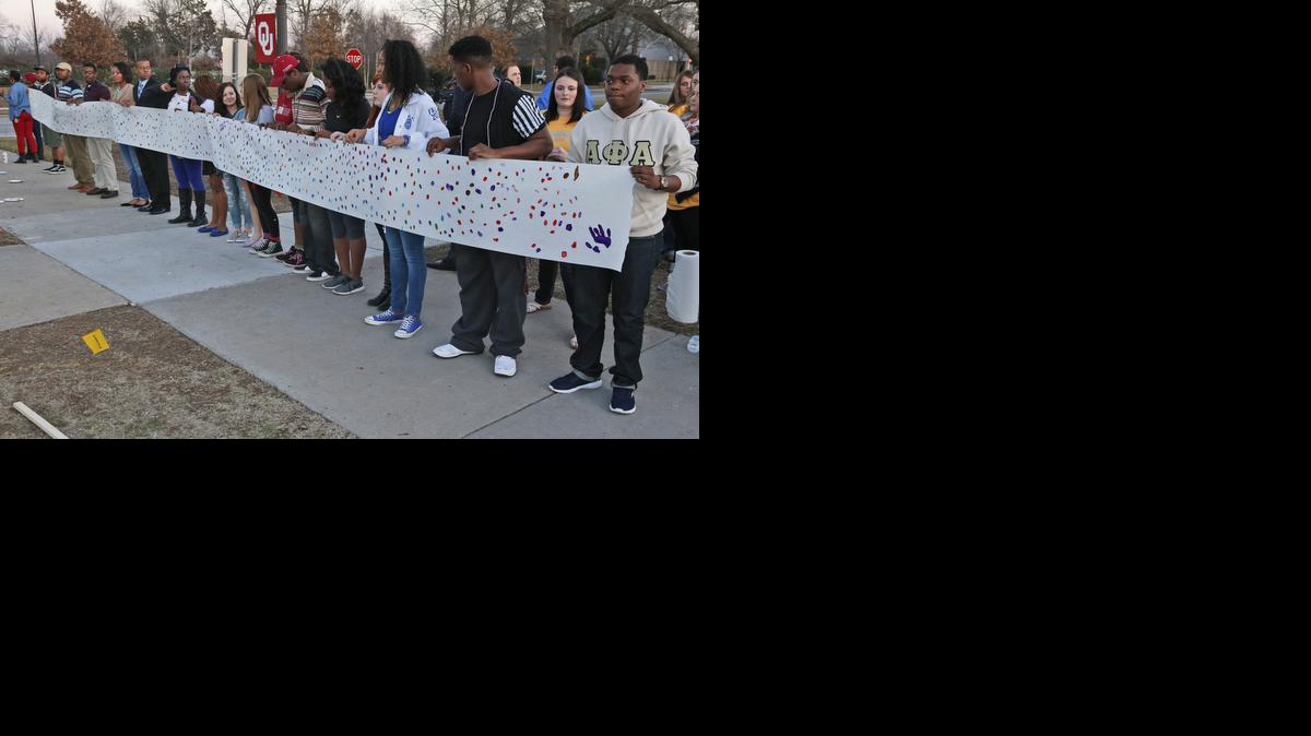 
University of Oklahoma students hold a sign to be carried to the now closed Sigma Alpha Epsilon fraternity house 
