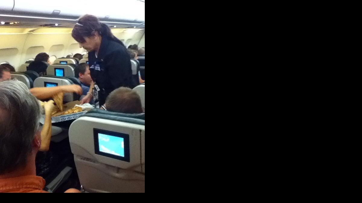 
In this photo taken Monday, July 7, 2014, a Frontier Airlines flight attendant passes out pizza to passengers aboard a Denver-bound flight diverted to Cheyenne, Wyo. 
