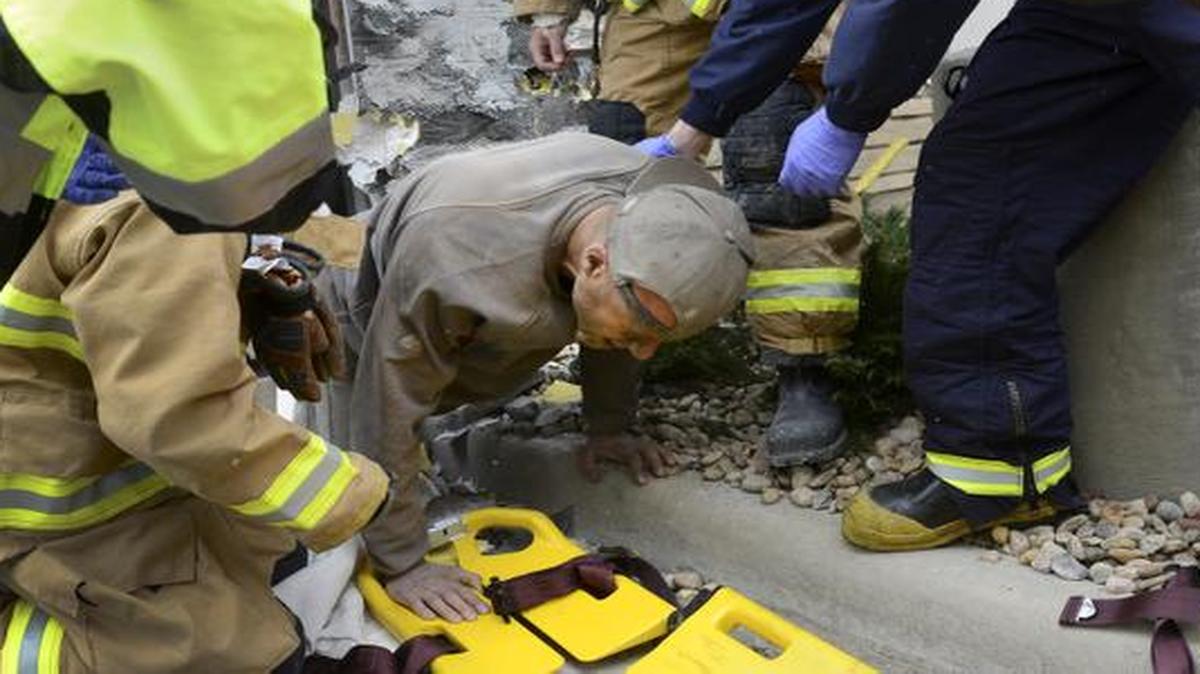 
A man trapped in a wall at the rear of Marshalls store crawls out of a hole and onto a backboard Tuesday
