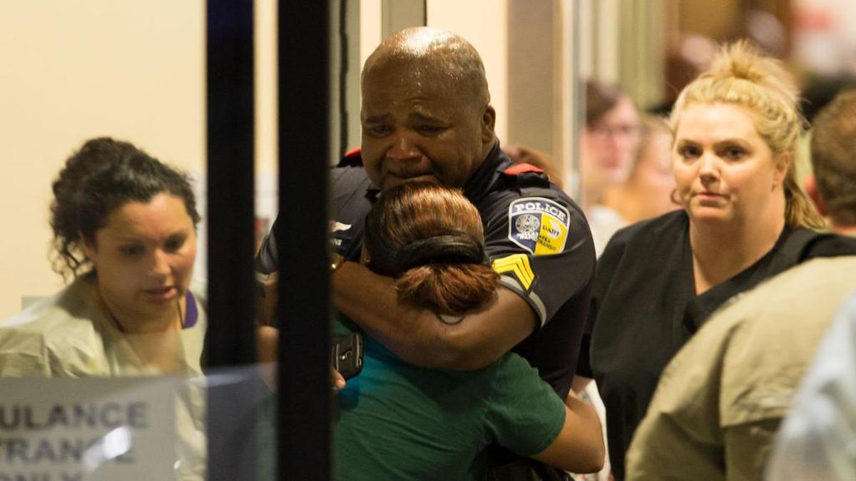 A Dallas Area Rapid Transit police officer received comfort at the Baylor University Hospital emergency room entrance Thursday.