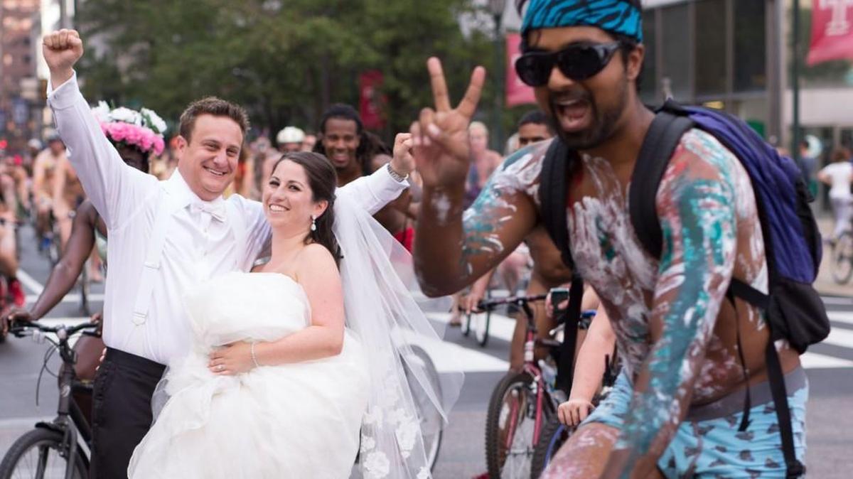 
Ross Cohen, left, and Blair Delson celebrate their wedding at the edge of Dilworth Plaza in Philadelphia, as participants in the annual Philly Naked Bike Ride pass by.
