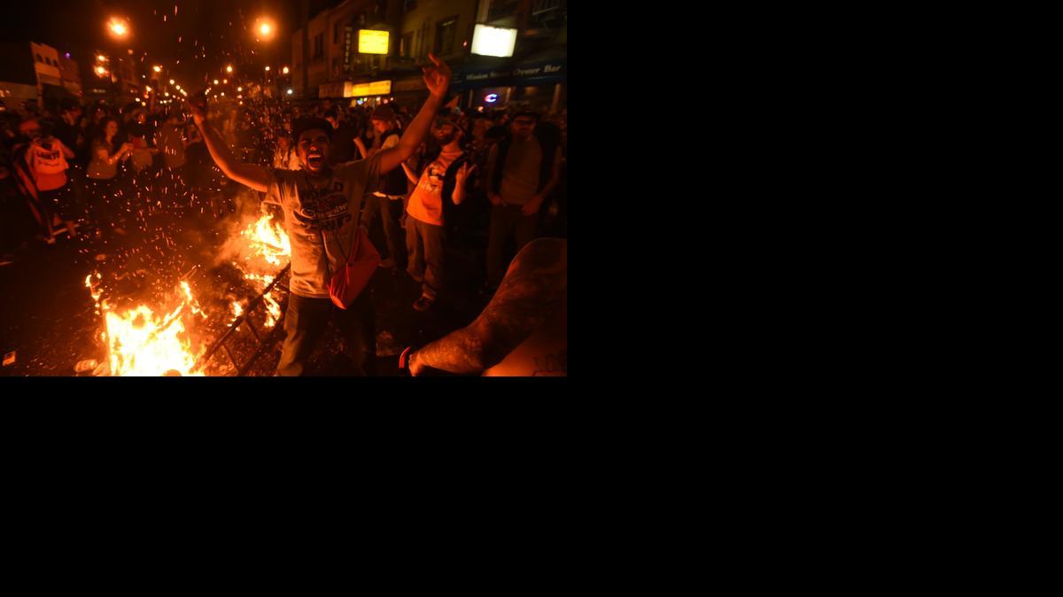 
San Francisco Giants fans celebrate next to debris that has been set on fire in the Mission district after the San Francisco Giants beat the Kansas City Royals to win the World Series 
