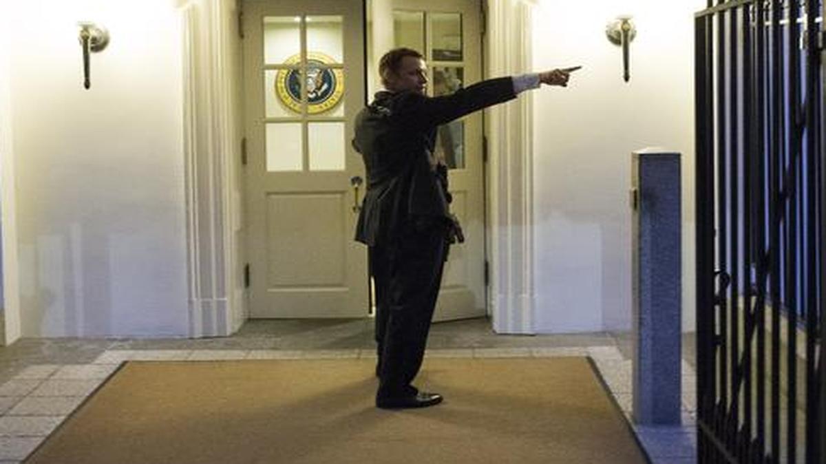 
A Secret Service agent gives directions during an evacuation from the White House minutes after President Barack Obama departed for Camp David aboard Marine One in Washington. 
