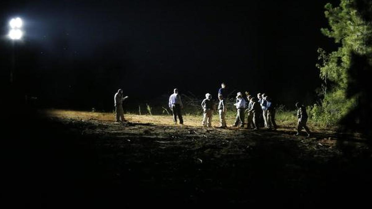 
A group of investigators gather under a light near the crime scene on Tuesday, Sept. 9, 2014, in Camden, Ala. 
