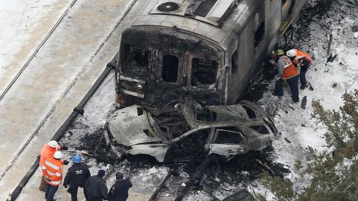 
The burned out shell of an SUV rests against a charred Metro-North Railroad commuter train 
