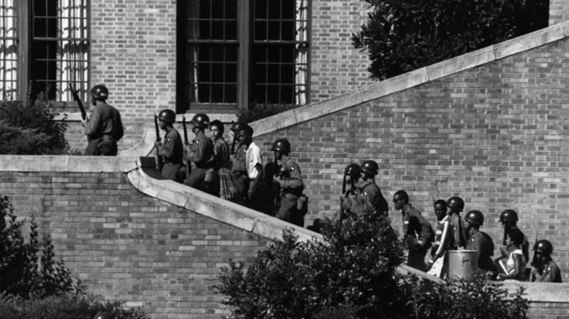 Black students known as the Little Rock Nine were escorted into Little Rock Central High School by the US Military in 1957, desegregating the school amid racist protests and harassment.
