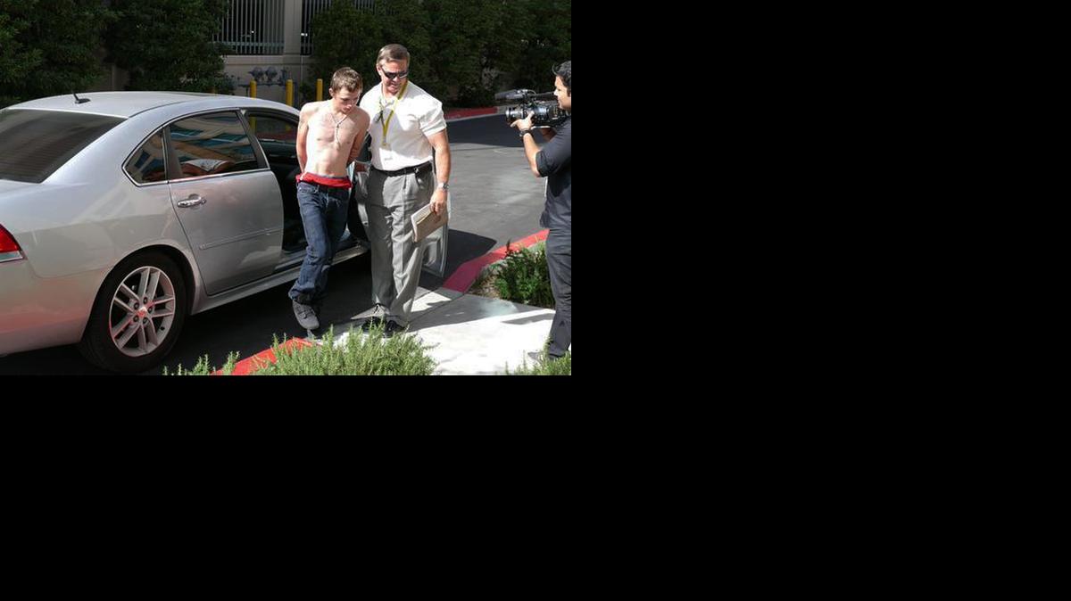 
A police officer leads Erich Nowsch, 19, from a car to police headquarters for questioning in Las Vegas
