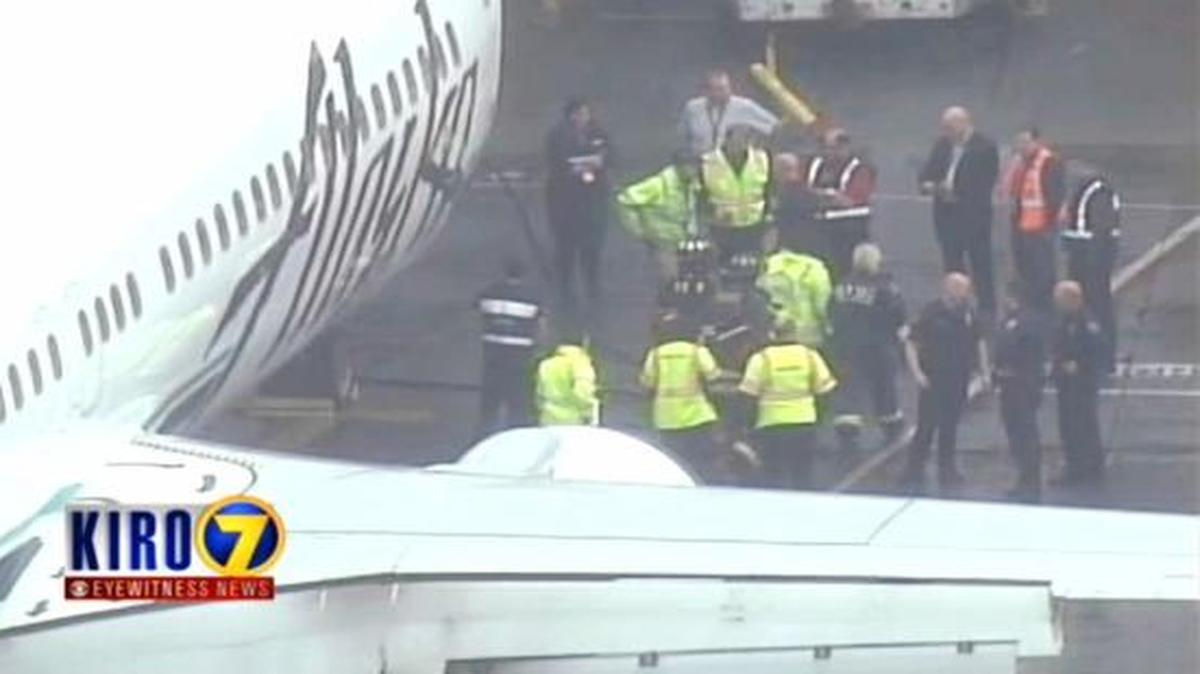 
In this frame from video, workers walk with a Menzies Aviation cargo worker after the worker was removed from the cargo hold of an Alaska Airlines airplane
