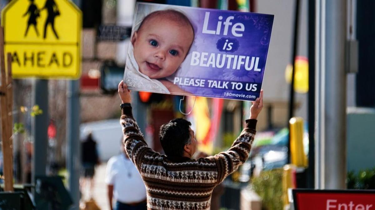 A protester carries a sign down the street near a Planned Parenthood health center in the Van Nuys section of Los Angeles on Saturday, Feb. 11, 2017.
