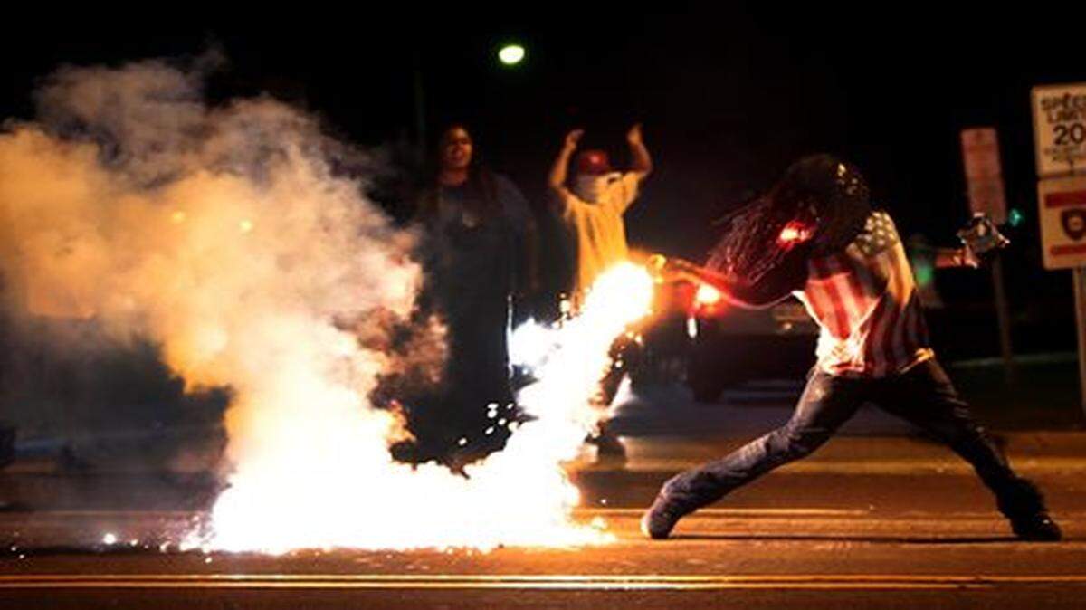 
A demonstrator throws back a tear gas container after tactical officers try to break up a group of bystanders Wednesday, Aug. 13, 2014 in West Florissant, Mo. Ferguson has been the site of nightly protests and unrest since 18-year-old Michael Brown was killed during a confrontation with an officer on Saturday. (AP Photo/St. Louis Post-Dispatch, Robert Cohen)

