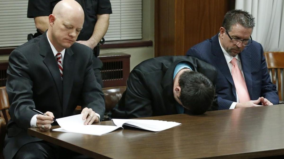 Daniel Holtzclaw, center, puts his head on the table and cries as the verdicts are read in his trial in Oklahoma City, Thursday. At left is defense attorney Robert Gray and at right is defense attorney Scott Adams.