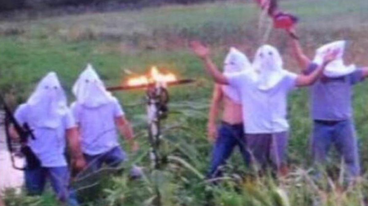 In this screen shot image taken from Twitter, five men wearing white hoods wave a Confederate flag next to a burning cross. The principal of Creston Community High School in southern Iowa says the school has disciplined several students who appeared in the photo, which circulated on social media, after officials became aware of it on Wednesday morning.