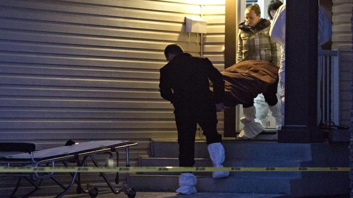 
The body of a victim is carried out of a home in Edmonton, Alberta, Tuesday. Nine people, including seven adults and two young children, were found dead at three separate crime scenes

