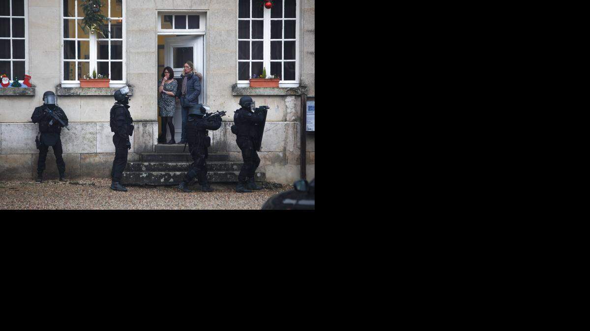 
French riot officers on Thursday patrolled in Longpont, north of Paris. Scattered gunfire and explosions shook France as the country held a day of mourning for 12 people slain at a Paris newspaper office. Police were hunting for two heavily armed brothers suspected in the massacre. 

