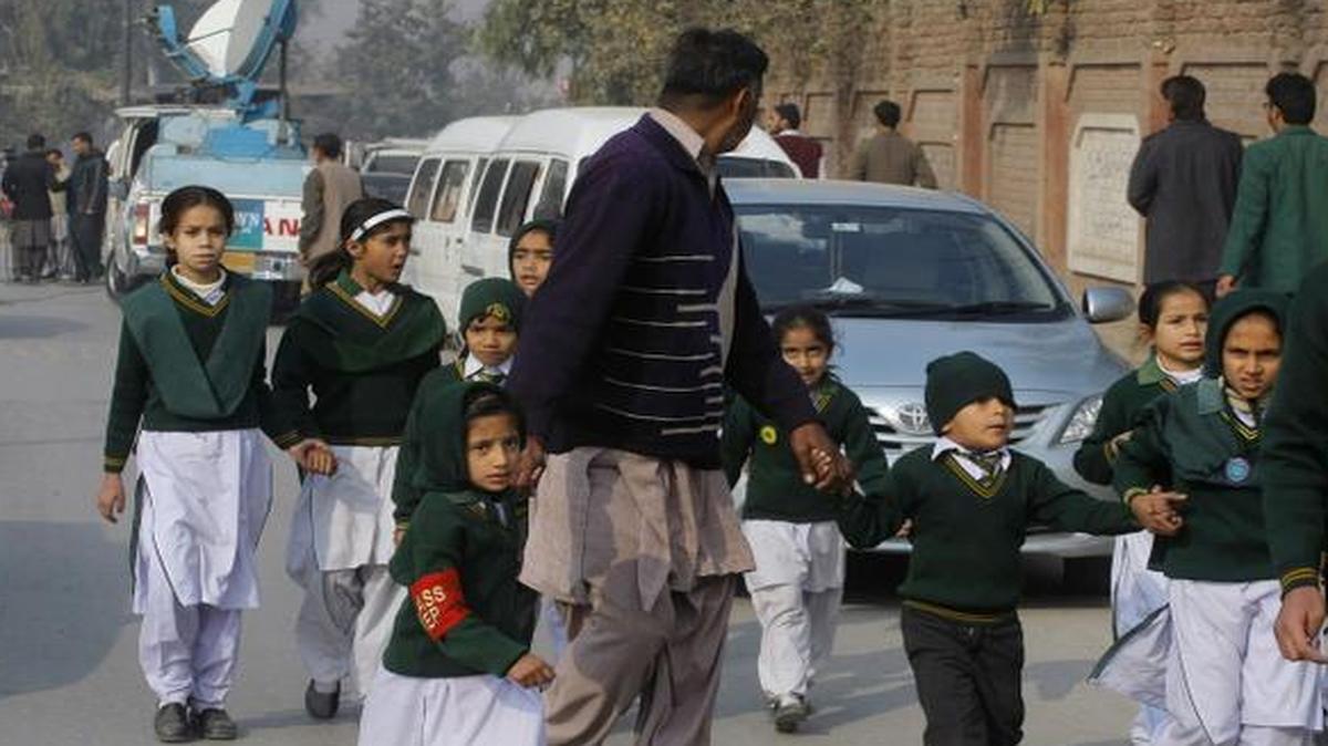 
A plainclothes security officer escorts students rescued from s school during a Taliban attack in Peshawar, Pakistan, Tuesday, Dec. 16, 2014. 
