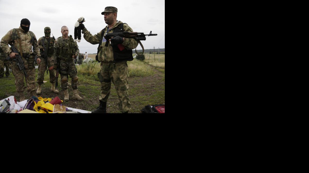 
A pro-Russian fighter holds up a toy found among the debris at the crash site of a Malaysia Airlines jet near the village of Hrabove, Friday, July 18, 2014. 
