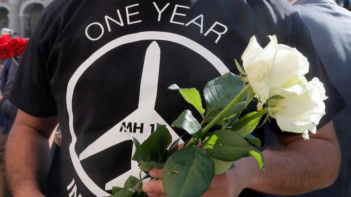 
Ukrainian men hold flowers as they offer them at the Netherlands Embassy for the Malaysia Airlines Flight MH17 crash victims, in Kiev, Ukraine, Friday, July 17. Residents of the Ukrainian village where the Malaysian airliner was shot down with 298 people aboard a year ago joined a procession to the crash site on Friday, while Australia's prime minister remembered the "savagery" of the disaster as he unveiled a plaque in Canberra that's set in soil from where the wreckage fell. 
