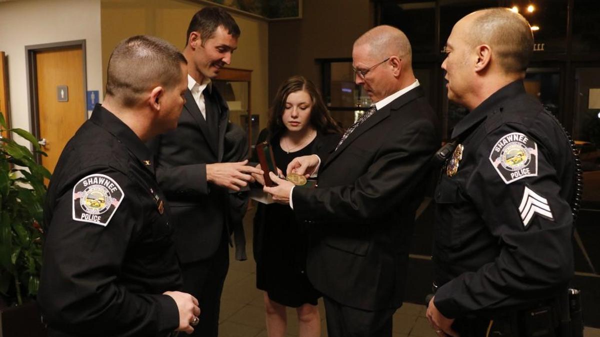 Local Good Samaritan Joshua Owen (second from left) showed off his Carnegie Medal, which received Monday during the Shawnee City Council meeting, to (from left) Shawnee Police Chief Rob Moser, his daughter Halle, his father Michael, and Shawnee Police Sergeant Craig Hermann.