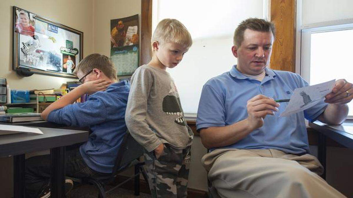
Josiah Gelatt (left), 12, and Ethan Gelatt, 9, worked on math with father Micah Gelatt at their home in Kansas City, Kan. The Gelatts are home-schooling four children.
