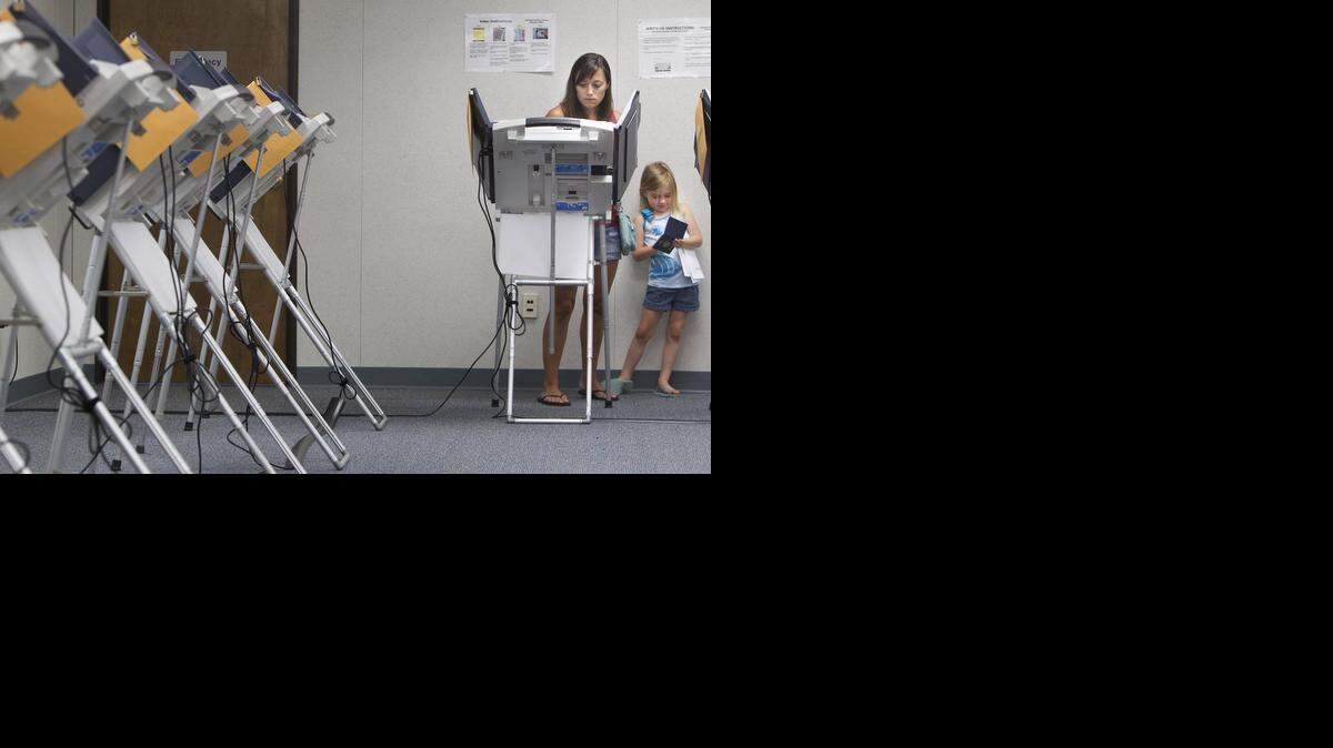 
Kansas voter Jennifer Ford of Olathe cast an early ballot as her daughters Jaelynn, 5, (right) and Juneau Ford, 2, (not in photo) waited for her to finish her civic duty on Monday, Aug. 4, 2014, during Early Voting at Johnson County Election Office, 2101 East Kansas City Rd., in Olathe. On Tuesday, polls in Kansas will be open from 7 a.m. to 7 p.m., while Missouri polling places will be open from 6 a.m. to 7 p.m.

