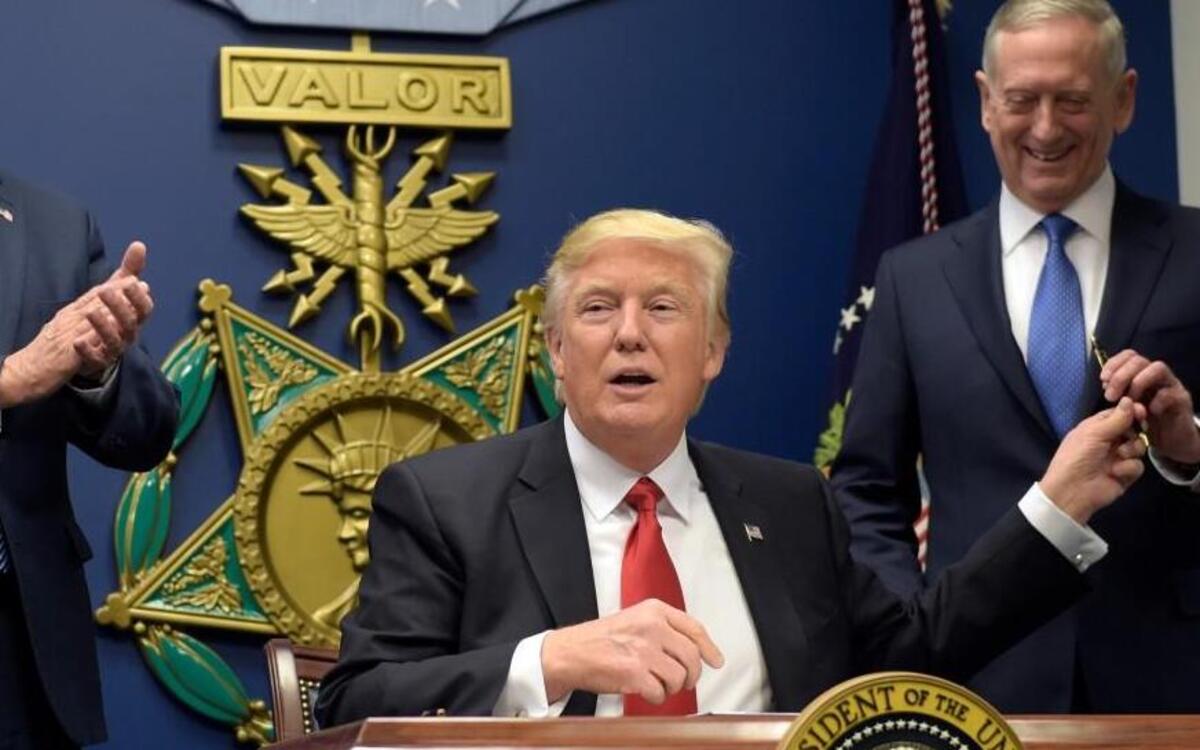 President Donald Trump, left, hands Defense Secretary James Mattis, right, a pen after he signed an executive action on rebuilding the military during an event at the Pentagon, Friday, Jan. 27, 2017.