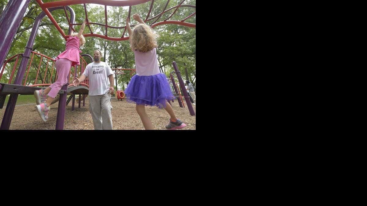 
Stay-at-home dad Paul Hemenway of Overland Park takes his three children to Franklin Park in Prairie Village about every other day. He recently played with his daughters Emma (left), 4, and Isabella, 6, on the park’s playground equipment.
