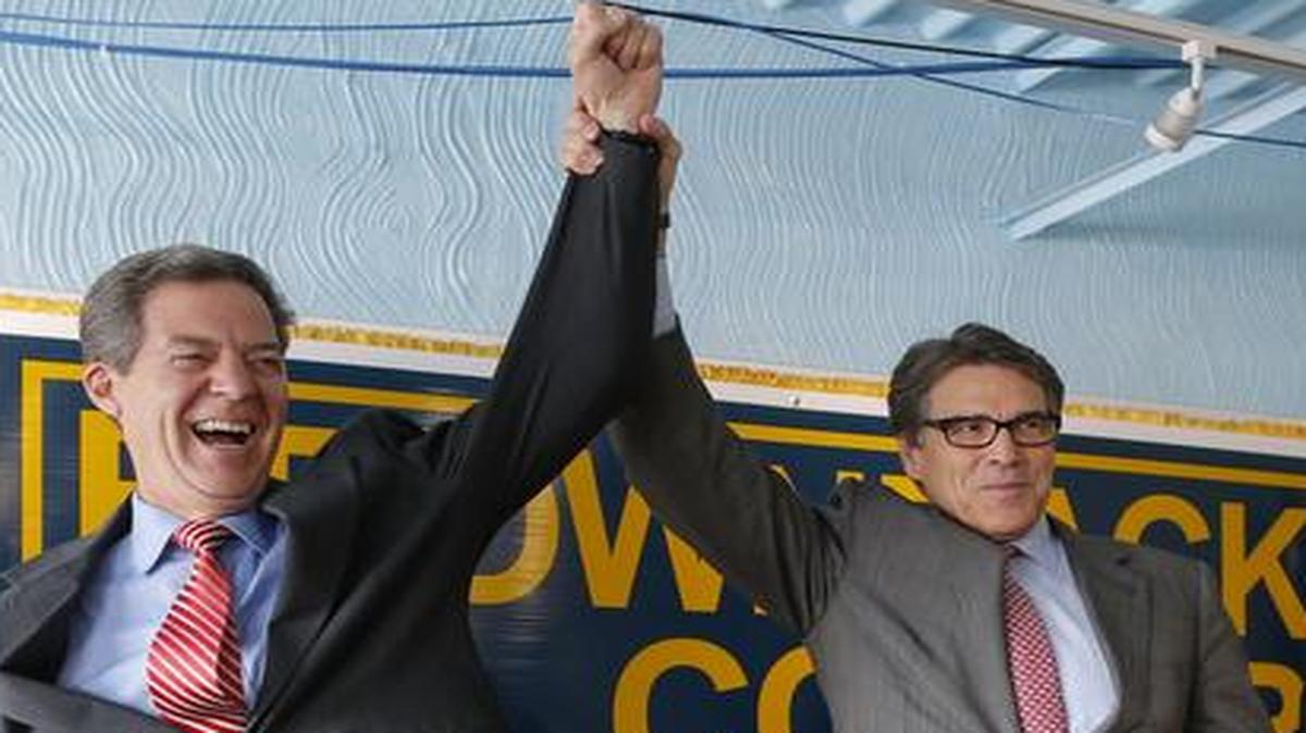 
Kansas Gov. Sam Brownback, left, has his arm raised in the air by Texas Gov. Rick Perry during a campaign rally for Brownback on Wednesday, Sept. 24, 2014 in Wichita.
