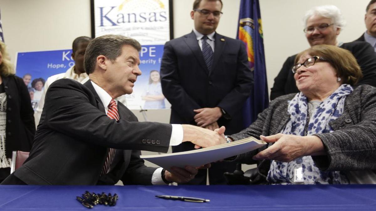 
Kansas Gov. Sam Brownback shook hands with Department for Children and Families secretary Phyllis Gilmore after signing a welfare reform bill into law last month in Topeka.
