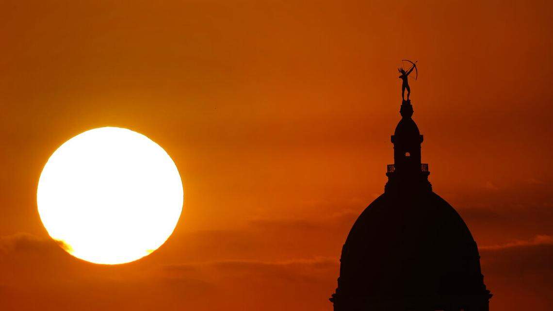 The Kansas Statehouse stands against the sky as the sun sets in the distance in Topeka.