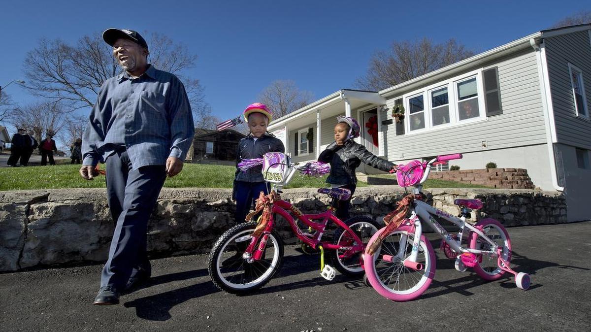 Artis Rollins and his twin 5-year-old daughters, Ariah (left) and Arielle, were given a renovated home in the Marlborough neighborhood on Tuesday through Jackson County’s Constructing Futures home giveaway. Included were two new bikes that the girls tried out in the driveway.