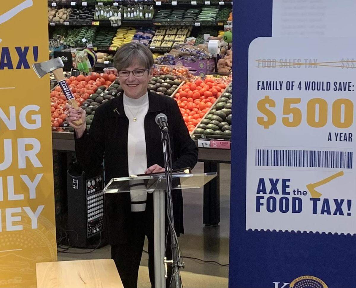 Kansas Gov. Laura Kelly holds a small axe on Monday during an event at Dillons in Topeka. Kelly is calling on lawmakers to eliminate the state sales tax on food, among the highest in the nation.