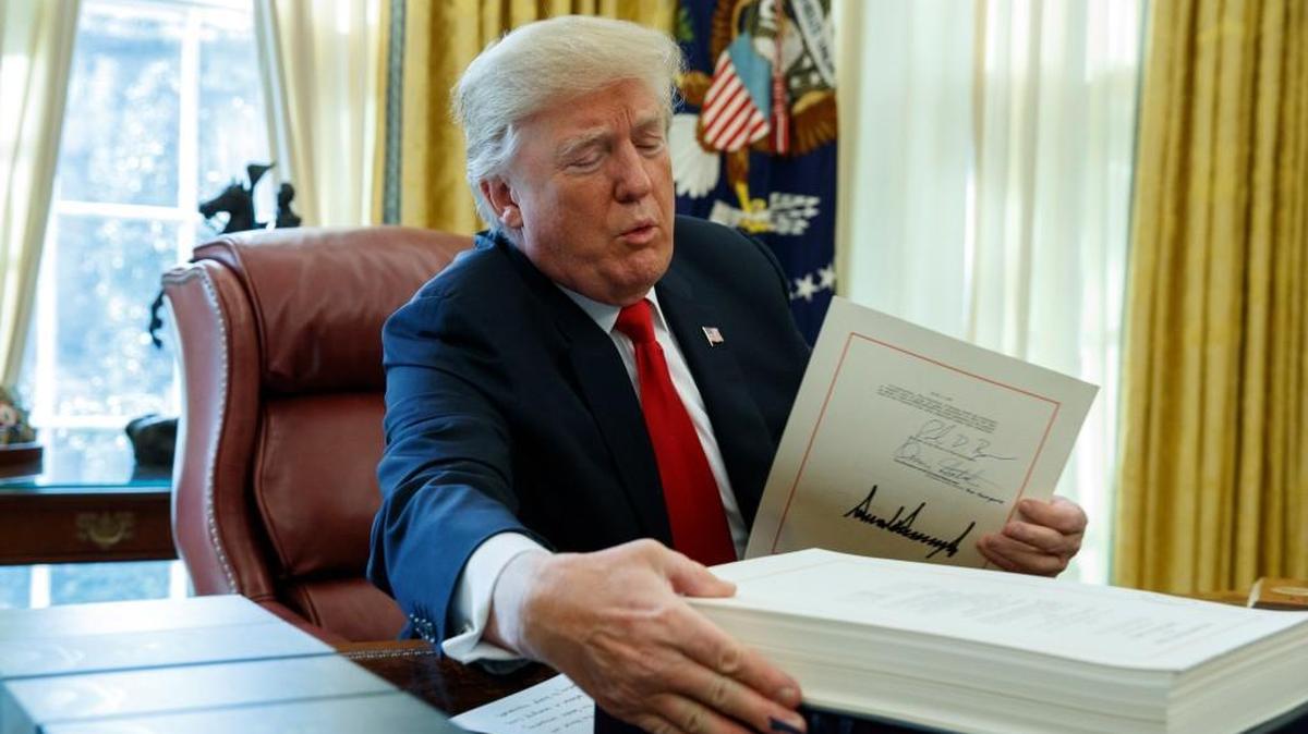 President Donald Trump grabs a box containing the tax bill after signing it in the Oval Office last week.