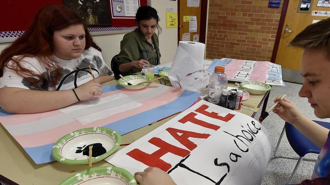 Caleb Bishop (right), Alaura Custard (left) and Brenna Hanisee, all students at Olathe North, prepare signs for a protest they will attend Friday at the Kansas Capitol in Topeka. Kansas lawmakers recently introduced a measure to require transgender students at public schools and universities to use restrooms that match their gender at birth, and student LGBT advocates in the state are crying foul. .