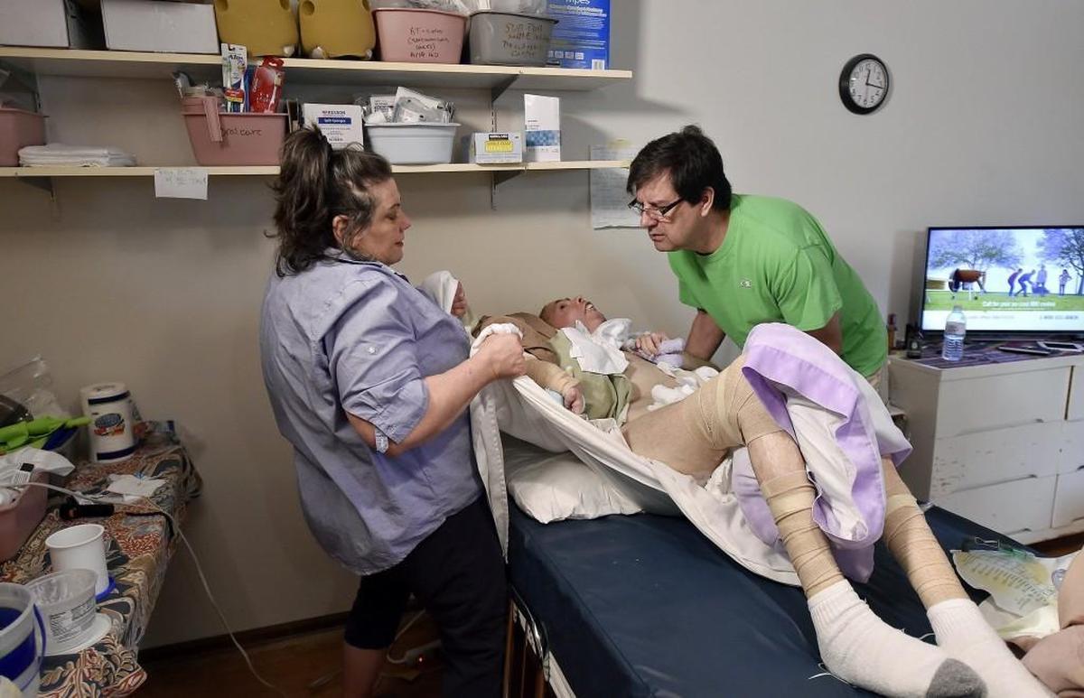 Vicki Distefano and her husband Mark Perbeck prepared to move her brother Mike onto his chair in their Fairway home. Mike Distefano suffered a traumatic brain injury in a motorcycle accident 11 years ago.
