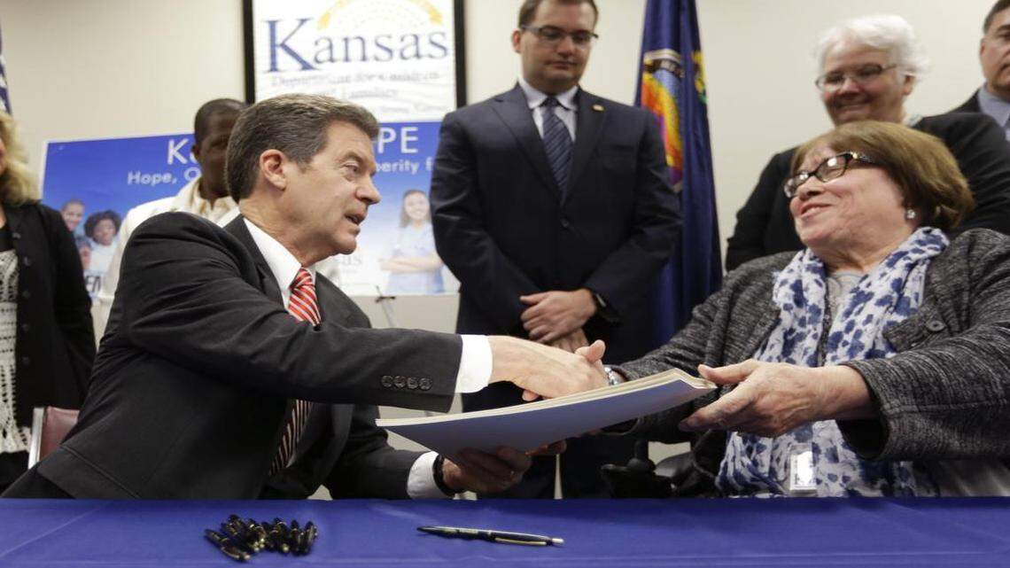 
Gov. Sam Brownback shook hands with Phyllis Gilmore, Department for Children and Families secretary, after signing a welfare reform bill into law Thursday in Topeka.
