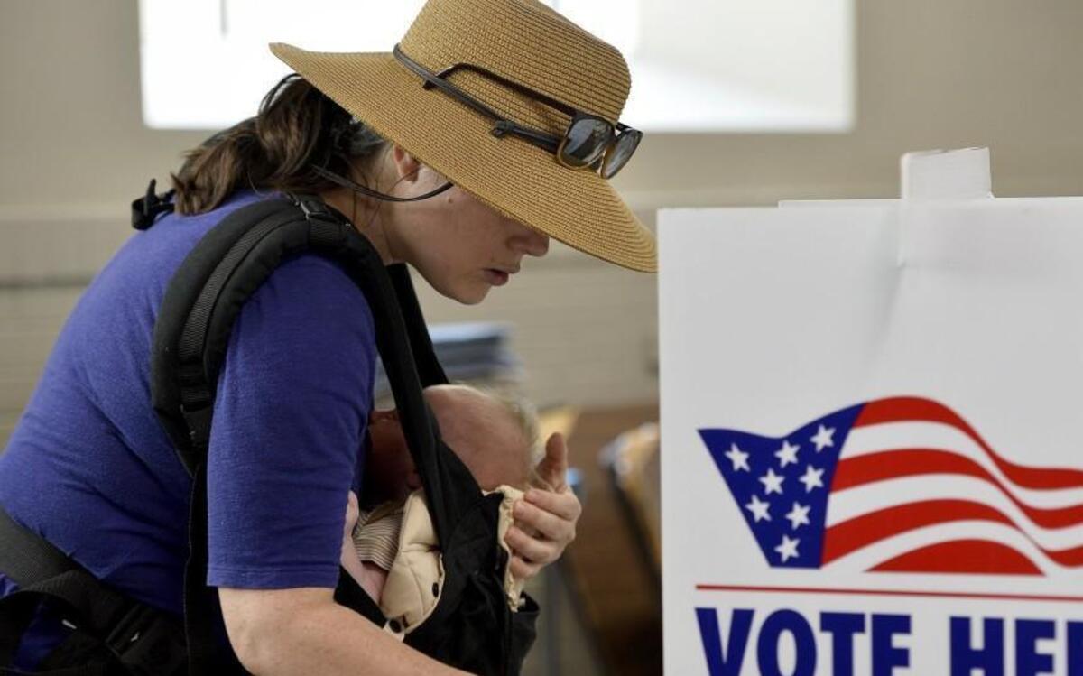 Holding 1-month-old Rosemary Webb, Anne Webb of the Hyde Park neighborhood double-checked her ballot Tuesday before submitting it at St. Paul’s Episcopal Church.