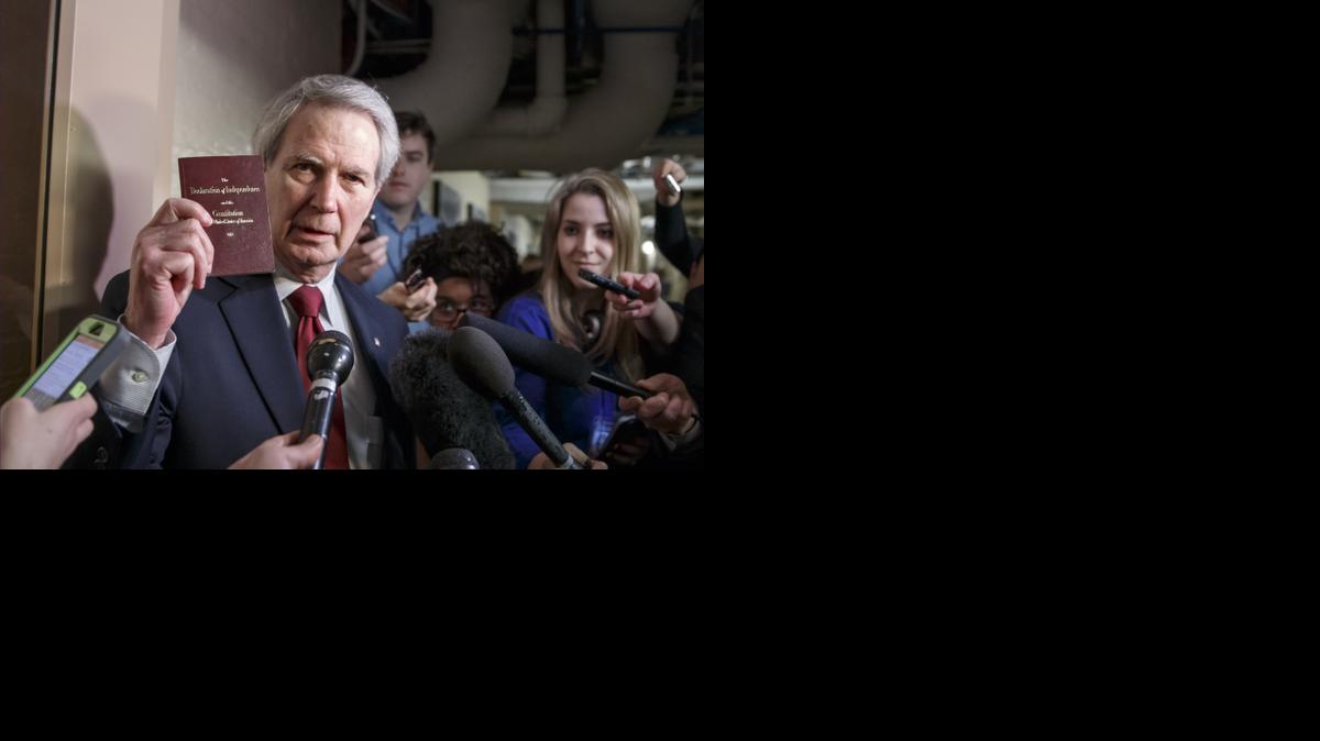 
Rep. Walter B. Jones, R-N.C., holds up a copy of the Constitution while talking to reporters as House Republicans emerge from a closed-door meeting on how to deal with the impasse over the Homeland Security budget.
