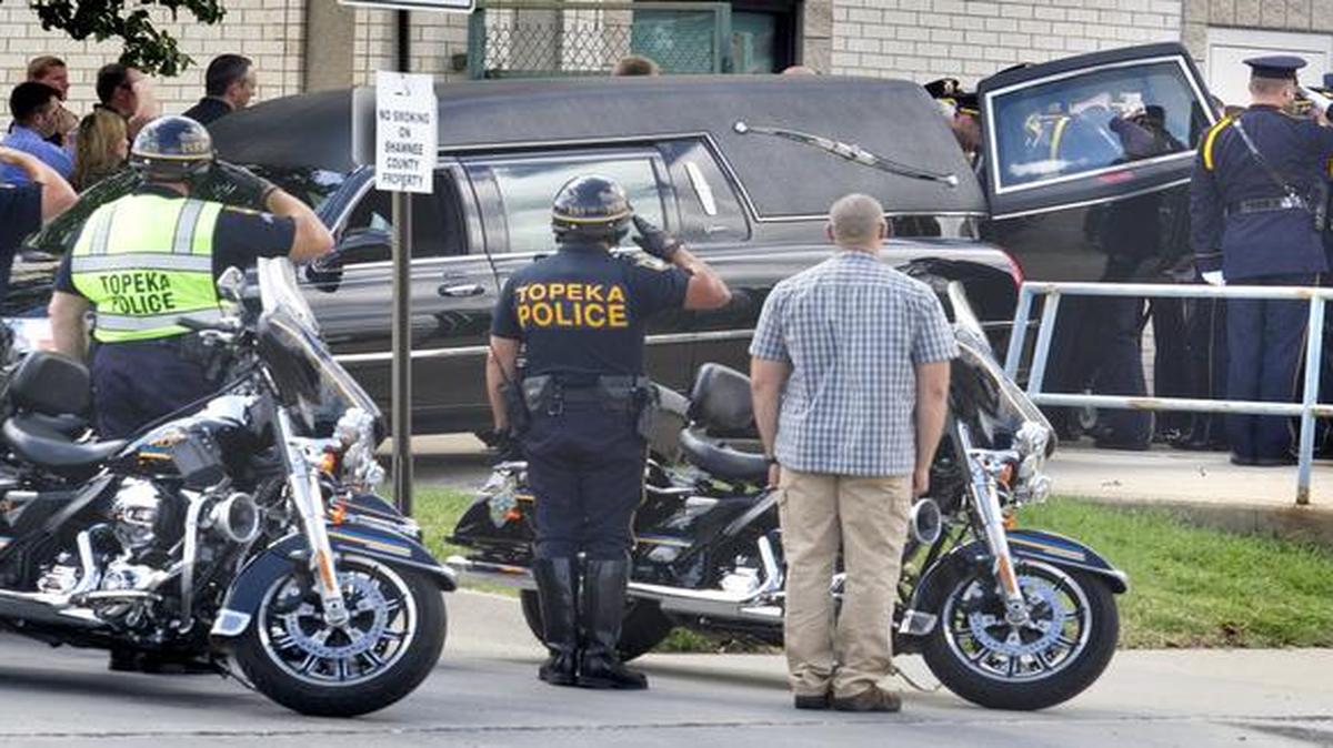 
Members of the Topeka Police Department stand at attention as the body of police Cpl. Jason Harwood is loaded into a hearse on Monday, Sept. 8, 2014 in Topeka.

