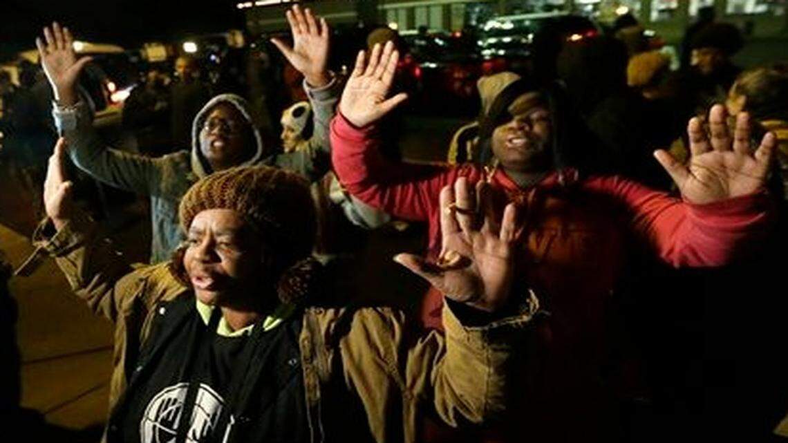 
Barbara Jones, joined by other protesters, raises her hands Monday in Ferguson, Mo., more than three months after an unarmed black 18-year-old man was shot and killed there by a white policeman. Ferguson and the St. Louis region are on edge in anticipation of the announcement by a grand jury whether to criminally charge Officer Darren Wilson in the killing of Michael Brown.
