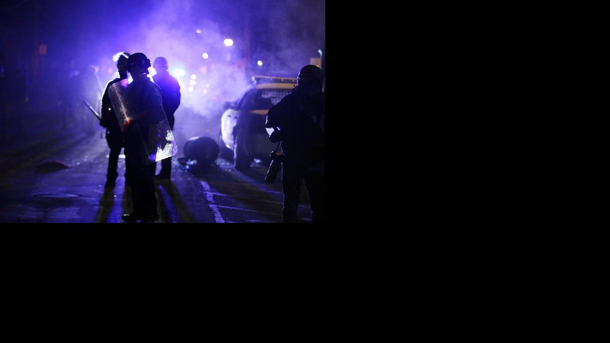 
Police officers watch protesters as smoke fills the streets in Ferguson, Mo., last November after a grand jury's decision in the fatal shooting of Michael Brown. 
