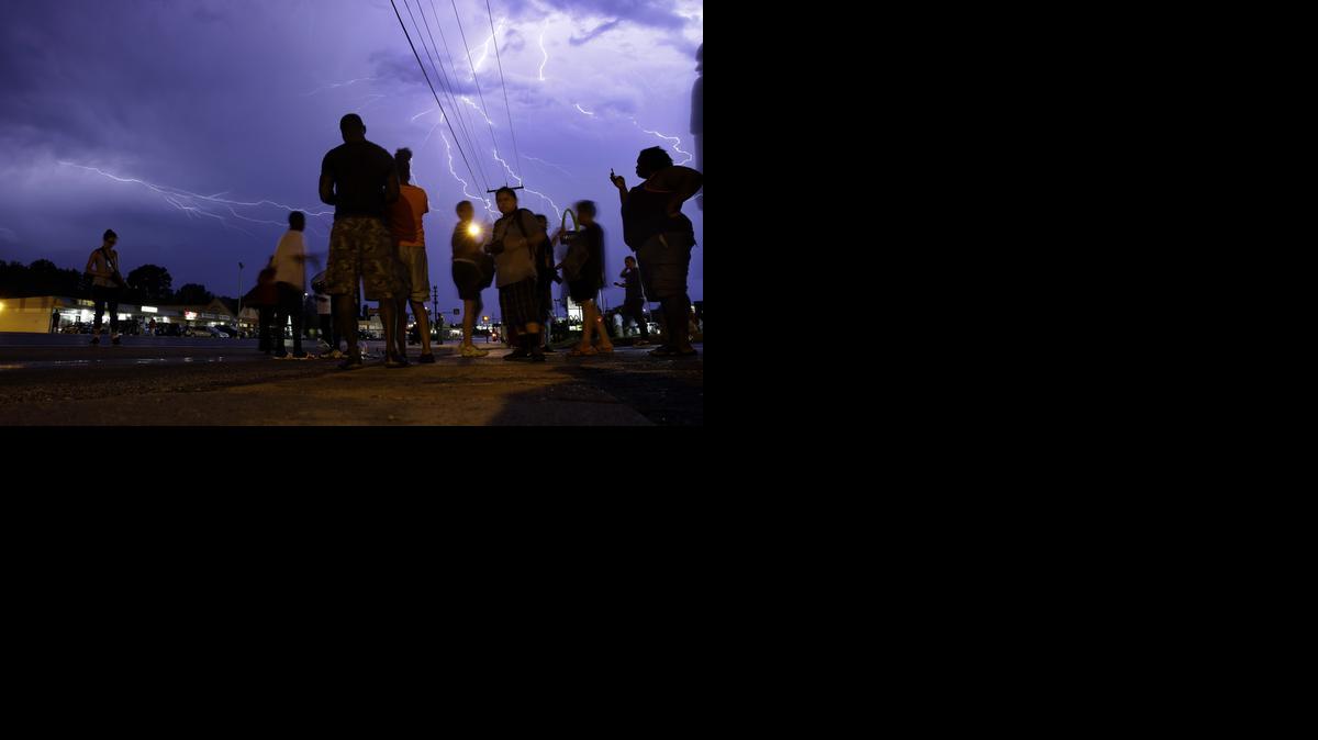 
Protesters stand in the street as lightning fills the night sky Wednesday, Aug. 20, 2014, in Ferguson, Mo.
