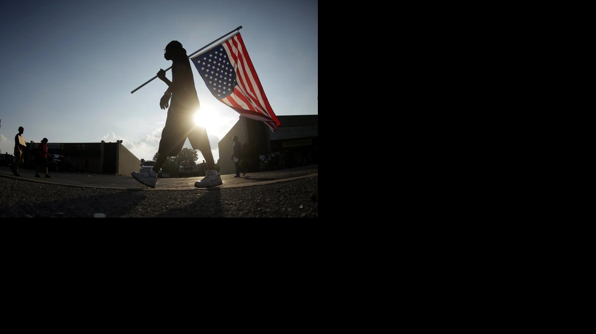 
Duane Merrells walkd with an upside down flag Monday at a protest for Michael Brown, who was killed by a police officer Aug. 9 in Ferguson, Mo. 
