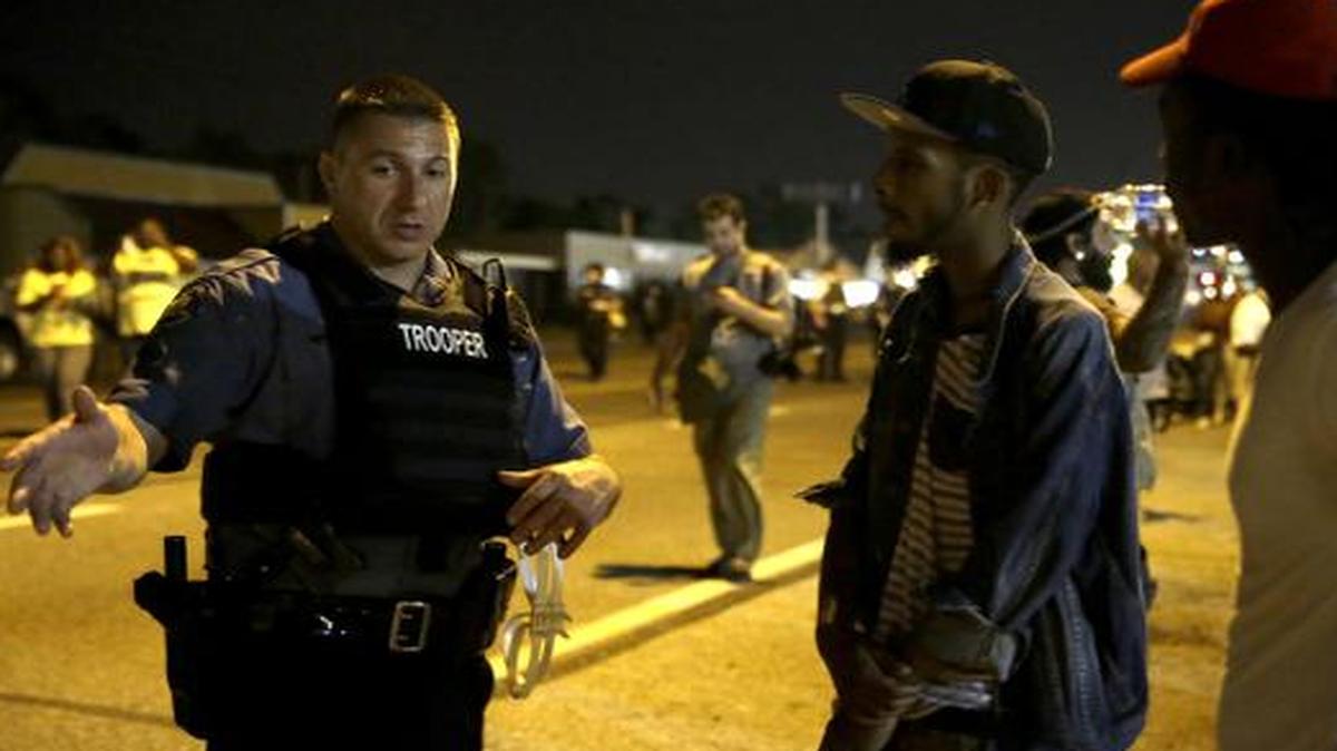 
A Missouri State trooper talks with protesters Tuesday, Aug. 19, 2014, in Ferguson, Mo. 
