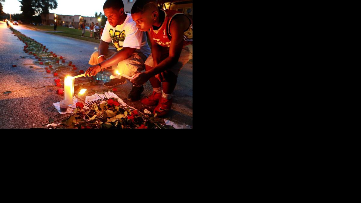 
Theo Murphy, left, of Florissant, Mo., and his brother Jordan Marshall, 11, light candles Thursday at a memorial on Canfield Drive in Ferguson, Mo.
