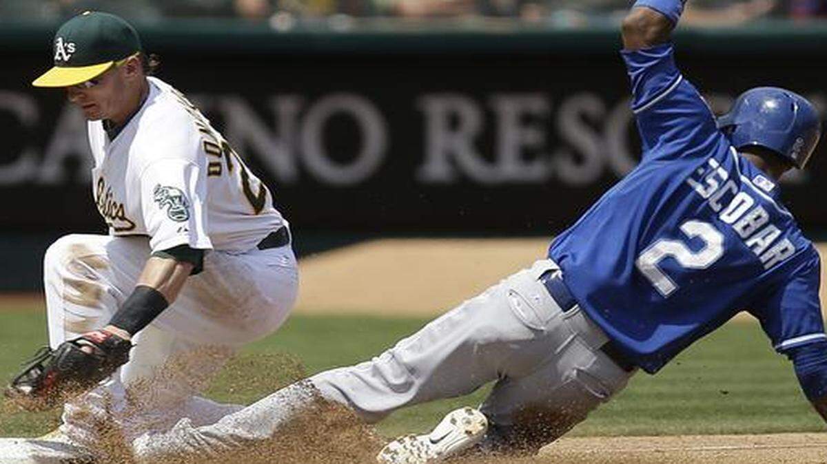 
The Kansas City Royals’ Alcides Escobar (right) advanced to third base past the tag of the Oakland Athletics’ Josh Donaldson in the fifth inning on Aug. 3. The Royals won 4-2.
