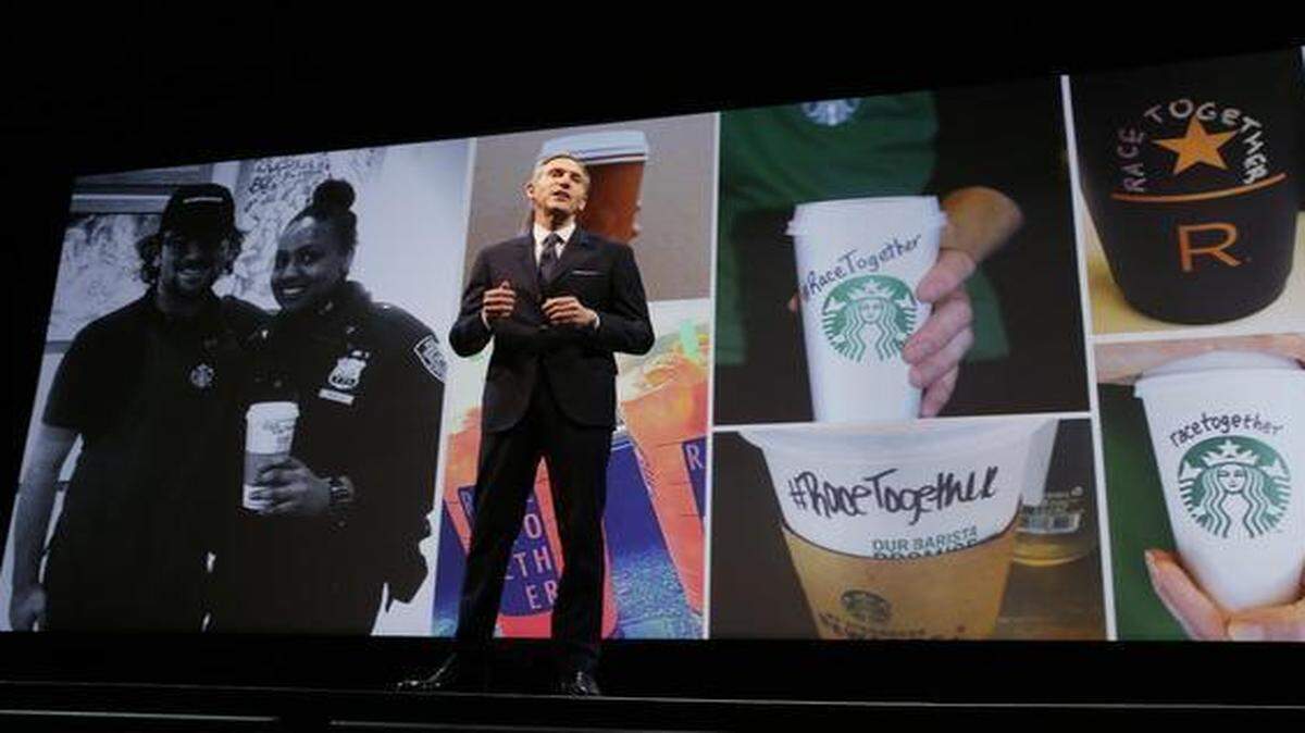 
Starbucks CEO Howard Schultz spoke while photos of coffee cups with #RaceTogether written on them were projected behind him.
