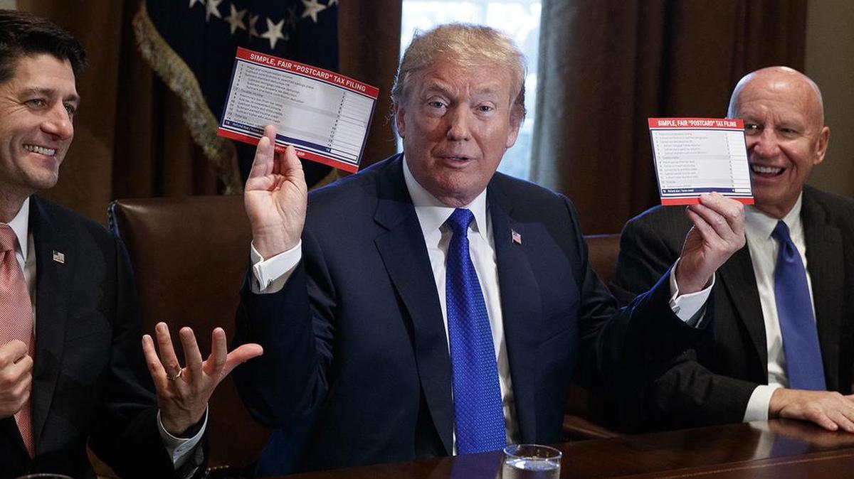 President Donald Trump holds an example of what a new tax form may look like during a meeting on tax policy with Republican lawmakers including House Speaker Paul Ryan Chairman of the House Ways and Means Committee Rep. Kevin Brady on Nov. 2.