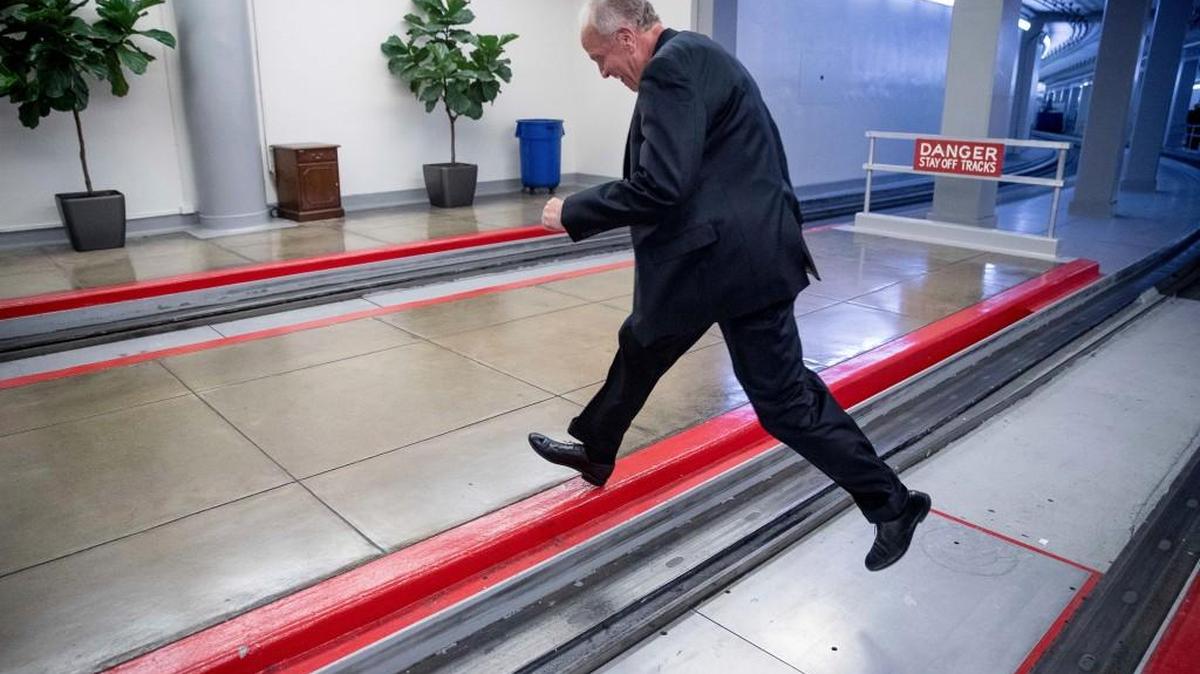 Sen. Jerry Moran jumps the tracks of the Senate subway on Capitol Hill in Washington, Tuesday, July 18, 2017, to get around a large gathering of reporters as he arrives on Capitol Hill.