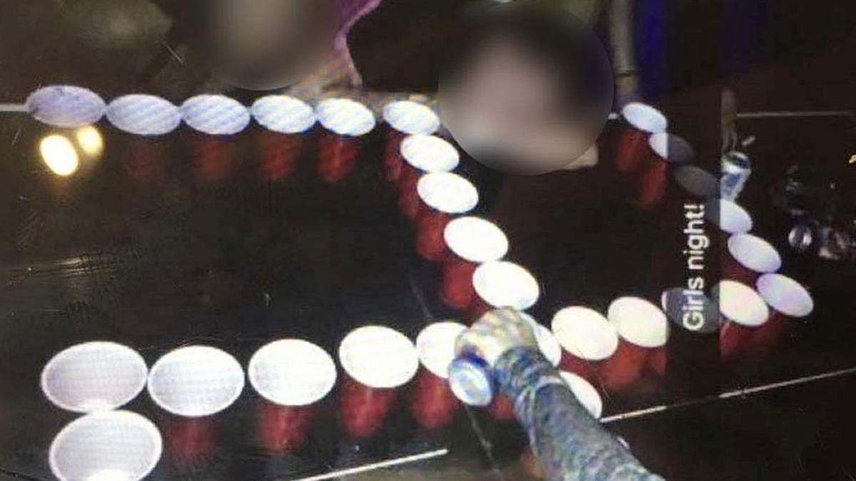St. Teresa’s Academy students, whose faces are blurred here, pose with a swastika made of beer pong cups.