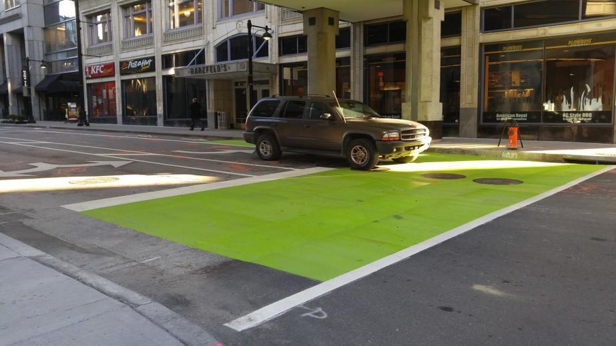 A sport utility vehicle moves through Kansas City’s first bike box downtown.